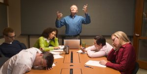 Boring presenter surrounded by students sleeping at the conference table