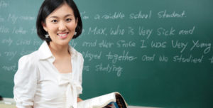 Asian teacher in front of a chalkboard