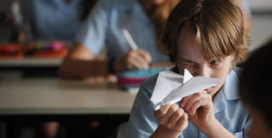 child examining a paper airplane