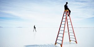 man sitting atop a very tall ladder