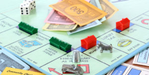 Monopoly game board with houses, hotels, money, dice, thimble, car and dog game pieces