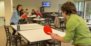 colleagues playing ping pong in company lunch room