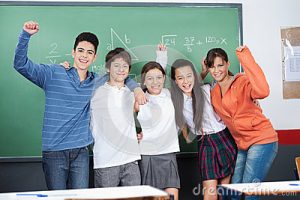 5 students cheering in front of a blackboard